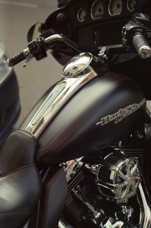Detailed close-up of a shiny Harley Davidson motorcycle parked outdoors.